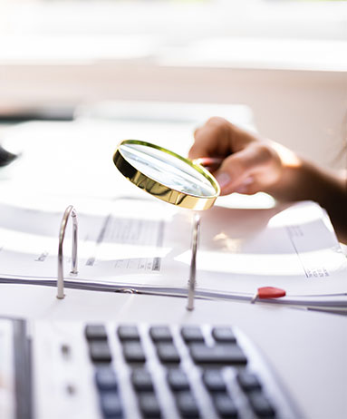 using magnifying glass to inspect documents