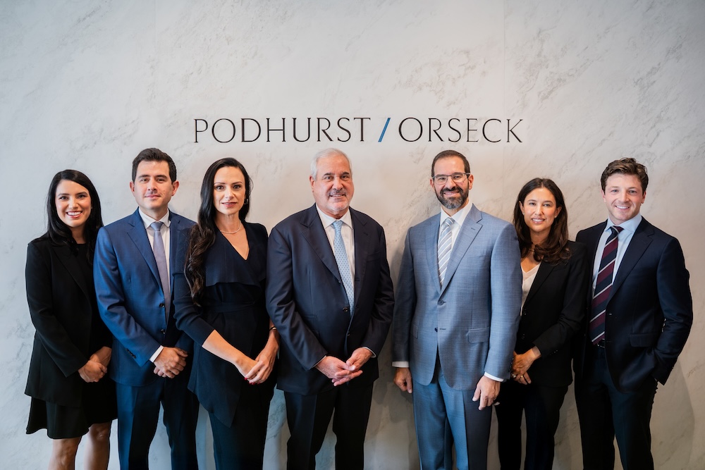 Seven of Podhurst Orseck's aviation litigation attorneys standing in front of a marble background with the firm's logo.